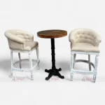 Elegant white bar chairs with cast iron legs paired with a round solid wood table.