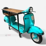 A vintage blue scooter transformed into a bar table, showcasing automobile-inspired furniture with an industrial touch.
