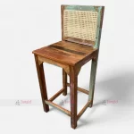 A colorful bar chair made from reclaimed upcycled wood, featuring and a vintage-style cane back.