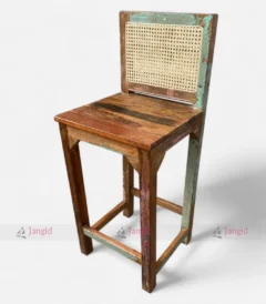 A colorful bar chair made from reclaimed upcycled wood, featuring and a vintage-style cane back.