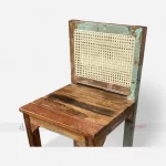 Closeup of A colorful bar chair made from reclaimed upcycled wood, featuring and a vintage-style cane back.