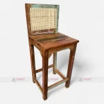 A colorful bar chair made from reclaimed upcycled wood, featuring and a vintage-style cane back.
