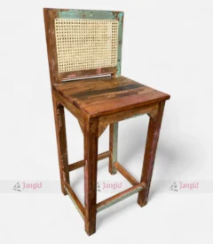 A colorful bar chair made from reclaimed upcycled wood, featuring and a vintage-style cane back.