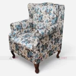 A floral wingback sofa chair featuring blue and white flowers, designed for elegance and comfort in hotel rooms or home spaces.