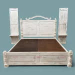 Hand-carved king-size hotel room bed with a wooden headboard, showcasing a white distressed finish for a classic, stylish look. Complemented by matching side tables.